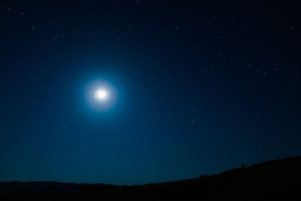 Céu noturno com lua cheia e estrelas.