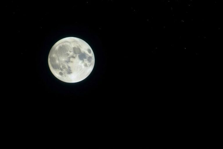 A lua iluminando o céu noturno com detalhes de sua superfície visíveis.